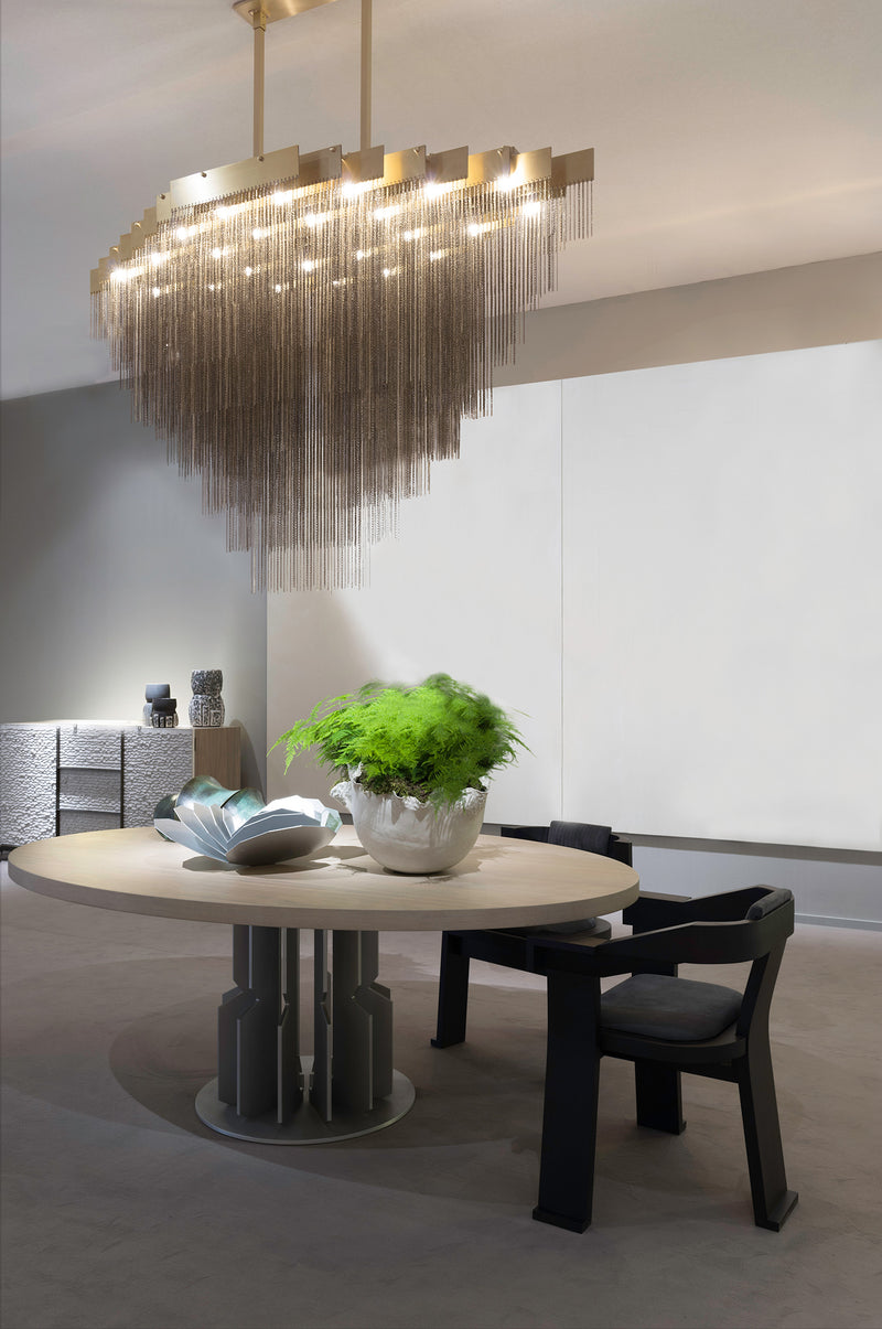 A luxury chandelier that moves with glamorous intrigue, the KELLY Chandelier’s metallic chain cascades through its various layers to create a glisten reflective effect. This contemporary light design creates a bold synergy of cold metal with warm light, a perfect addition to modern interior design.